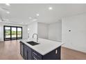 Modern kitchen with island, stainless steel appliances, and hardwood floors offers luxurious features and open layout at 18773 Dayspring Pl, Venice, FL 34293