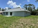 Backyard view showcasing the house, sliding glass doors, and lush green grass at 5018 Wagon Wheel Dr, North Port, FL 34291