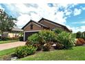Single-story home exterior with lush landscaping and a two-car garage at 8744 Bellussi Dr, Sarasota, FL 34238