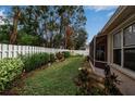 Landscaped backyard with a screened patio and a white fence at 11867 Hollyhock Dr, Lakewood Ranch, FL 34202