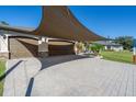 Spacious paver driveway with shade sail and three-car garage at 4457 Maywood Ln, North Port, FL 34286