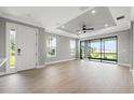 Spacious living room with neutral walls, wood floors, tray ceiling, and a sliding glass door to the outside at 3118 Tramonto Ct, Bradenton, FL 34211