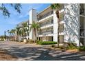 Condo building with multiple balconies, palm trees, and lush landscaping at 4600 Gulf Of Mexico Dr # 203, Longboat Key, FL 34228