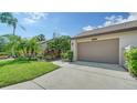 View of attached garage with lush landscaping at 5956 Clubside Dr # 7651, Sarasota, FL 34243