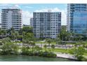 A view of condo building from across a waterfront, featuring large windows and manicured green space at 555 S Gulfstream Ave # 804, Sarasota, FL 34236