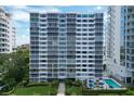 View of a condo building featuring a meticulously landscaped yard, a refreshing pool, and ample lounging space at 555 S Gulfstream Ave # 804, Sarasota, FL 34236