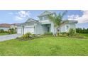 Two-story house with light teal exterior, three car garage, and landscaped lawn at 12420 Destin Loop, Venice, FL 34293