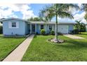 Light blue house with a palm tree, well-manicured lawn, and a white garage door at 22119 Laramore Ave, Port Charlotte, FL 33952