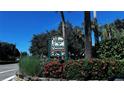 Village Gardens community sign surrounded by lush landscaping and vibrant red flowers at 5071 Village Gardens Dr # 5, Sarasota, FL 34234