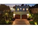 A nighttime view of the front exterior of a two-story home featuring a two-car garage and accent lighting at 1884 Grove St, Sarasota, FL 34239