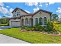 Two-story house with tan exterior, arched entryway, and landscaped yard at 14607 Swiss Bridge Dr, Lithia, FL 33547