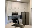 Close-up of the kitchen featuring white cabinetry, stainless steel appliances, and a stylish backsplash at 5152 Northridge Rd # 302, Sarasota, FL 34238
