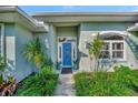 Inviting front entrance with a bright blue door, detailed trim, and verdant landscaping at 7235 Rangi Dr, Sarasota, FL 34241