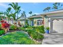 Beautiful home exterior featuring lush tropical landscaping and an attached two-car garage at 7235 Rangi Dr, Sarasota, FL 34241