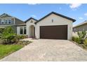 Attractive single-story residence featuring a two-car garage, lush landscaping, and a brick driveway at 774 Hillshire Pl, Spring Hill, FL 34609