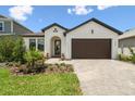 Beautiful home with a manicured lawn, modern front door, and a brick-paved driveway leading to a two-car garage at 774 Hillshire Pl, Spring Hill, FL 34609