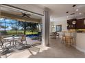 Indoor/outdoor living space with a full kitchen bar and dining table that overlooks a screened pool and golf course at 14508 Stirling Dr, Lakewood Ranch, FL 34202