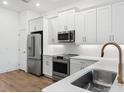 Modern kitchen featuring stainless steel appliances, white cabinets, quartz countertops, and wood-style flooring at 1625 Compass Pointe Ct # 105, Punta Gorda, FL 33950