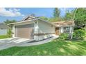 Newly renovated home with a brown garage door and a landscaped yard at 8212 Country Oaks Ct, Sarasota, FL 34243