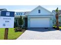 Charming, light blue single Gathering home with a pristine white garage door and paver driveway at 705 Anegada Ln, Sarasota, FL 34234
