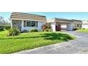 Front view of a single story home with attached garage and well-manicured lawn at 2607 Riverbluff Pkwy # V145, Sarasota, FL 34231