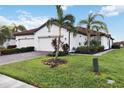 White two-car garage home with tile driveway, landscaping, and palm trees at 11722 Bluebird Pl, Bradenton, FL 34211