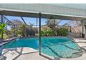 Inviting screened-in pool featuring a hot tub and tropical landscaping, perfect for outdoor enjoyment at 218 Brandywine Circle, Englewood, FL 34223