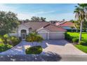 Charming beige single-story home with a red tile roof, lush landscaping, and a paver driveway at 2921 Seasons Blvd, Sarasota, FL 34240