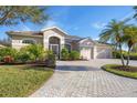 Tan, single-story house with a paved driveway and landscaping at 2921 Seasons Blvd, Sarasota, FL 34240