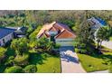 House with tile roof and driveway, surrounded by trees and landscaping at 21 Bayhead Ln, Osprey, FL 34229