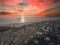 Stunning aerial view of a beachfront building, expansive parking lot, and nearby community at sunset at 1055 Beach Rd # B-302, Sarasota, FL 34242
