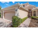 Exterior angle of a beige home showcasing brick pavers leading to an arched doorway and three car garage at 650 Crane Prairie Way, Osprey, FL 34229