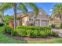 Single-story home with tan exterior, two-car garage, and mature landscaping at 7116 Presidio Gln, Lakewood Ranch, FL 34202
