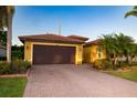 Yellow house with brown garage door and landscaping at 6935 74Th Street E Cir, Bradenton, FL 34203