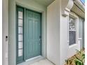 A close up of the beautiful blue-green front door with sidelight, adding curb appeal at 10444 48Th E Ct, Parrish, FL 34219