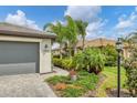 Gray three-car garage with a landscaped walkway, and a view of neighboring houses at 15967 Clear Skies Pl, Lakewood Ranch, FL 34211