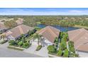 An aerial view of a neighborhood with a lake, lush landscaping, and well-maintained houses with tile roofs at 7011 Woodmore Ter, Lakewood Ranch, FL 34202