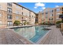 Community swimming pool with surrounding brick patio and lounge chairs at 4221 W Spruce St # 1326, Tampa, FL 33607