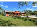 Brick ranch home with orange siding, mature landscaping, and a spacious front yard at 2971 71St E Ave, Sarasota, FL 34243