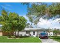 Ranch style home with a tree in front and a car parked in the driveway at 4457 Brooksdale Dr, Sarasota, FL 34232