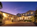 A well-lit, two-story home boasting an attached three car garage and a brick paved drive way at twilight at 1243 Starboard Ln, Sarasota, FL 34242