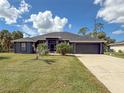 Single-story home with gray exterior, two-car garage, and lush landscaping at 1661 Atwater Dr, North Port, FL 34288