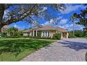 Beautiful single-story home with a tile roof, elegant columns, lush landscaping, and a paver driveway at 10209 Discovery Ter, Bradenton, FL 34212
