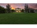 Expansive backyard featuring lush green grass, mature trees, and a screened-in lanai on the home's rear at 12224 Longview Lake Cir, Bradenton, FL 34211