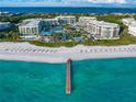 Stunning aerial view of beachfront resort with a private pier, white sandy beach, and turquoise waters at 1561 Gulf Of Mexico Dr # 403, Longboat Key, FL 34228