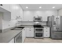 Modern kitchen with white cabinets, stainless steel appliances, and gray countertops at 3880 Ironwood Ln # 208E, Bradenton, FL 34209