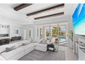 Bright living room features beamed ceilings, a plush sectional sofa, and sliding glass doors to the outdoor pool area at 5910 Gulf Of Mexico Dr, Longboat Key, FL 34228