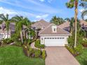 Charming home with a lush landscaped front yard, brick driveway, and a two-car garage, all under a blue sky at 7139 Sandhills Pl, Lakewood Ranch, FL 34202