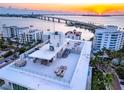 A building rooftop with lounge and dining areas, overlooking the water and a nearby bridge at sunset at 111 Golden Gate Pt # 602, Sarasota, FL 34236