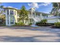 Eye-level view of a light green two-story building with a metal roof and lush landscaping at 294 Hidden Bay Dr # 203, Osprey, FL 34229